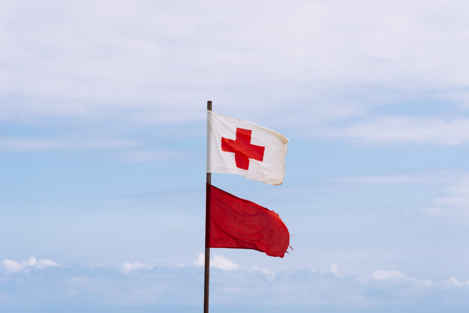 A photo of Red Cross flags flying in the air to represent Entry Level NGOs to work for in the Humanitarian Aid sector