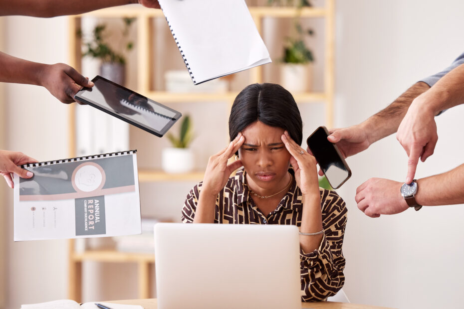 A woman sitting at a desk with her hands on her head symbolizing burnout in the humanitarian aid sector