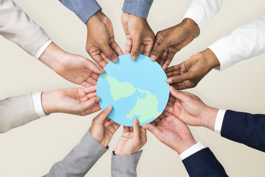 A group of hands holding a paper cut out of the earth to symbolize humanitarian aid and development aid