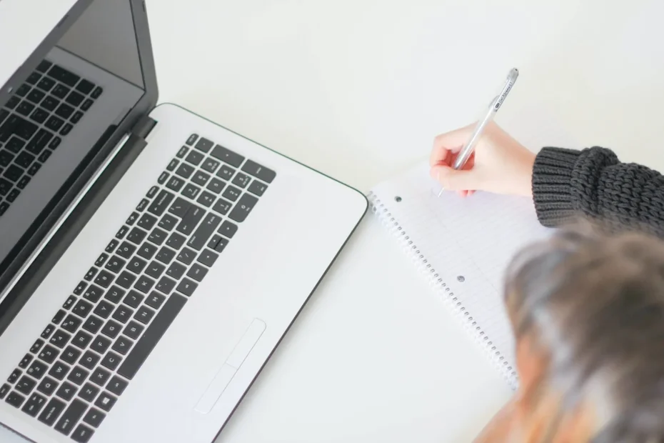 A person sitting with a laptop and writing on a paper representing looking for international NGO jobs