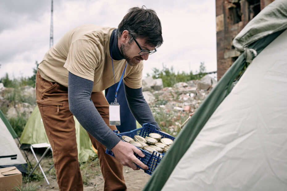 A man handing out aid to people in tents to symbolize reasoning to work in humanitarian aid