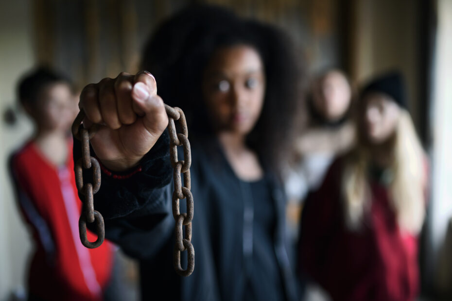 Black woman holding a chain in her hand symbolizing human rights abuses such as human trafficking