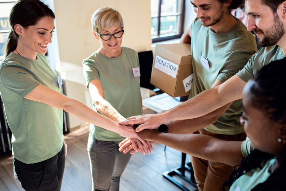 a photo of a team of NGO workers with their hands in a pile to signify team work