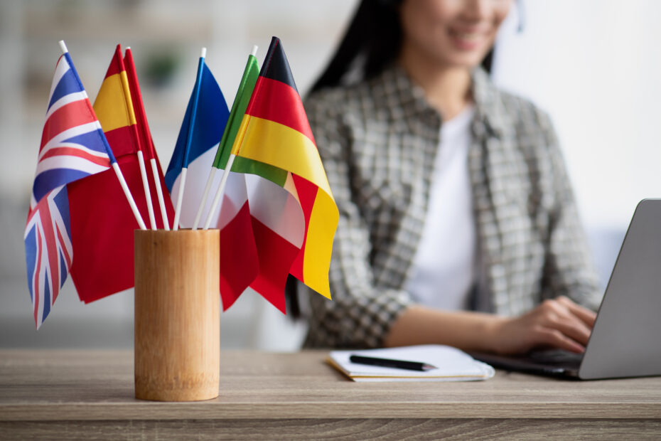 A girl sitting at a desk with a laptop, paper, and world flags representing the UN official languages