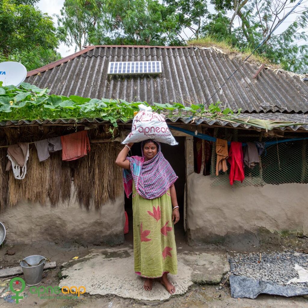 An Indian woman infront of her house receiving food and supplies from Apne Aap NGO in India, an anti-sex trafficking organization supporting marginalized women.