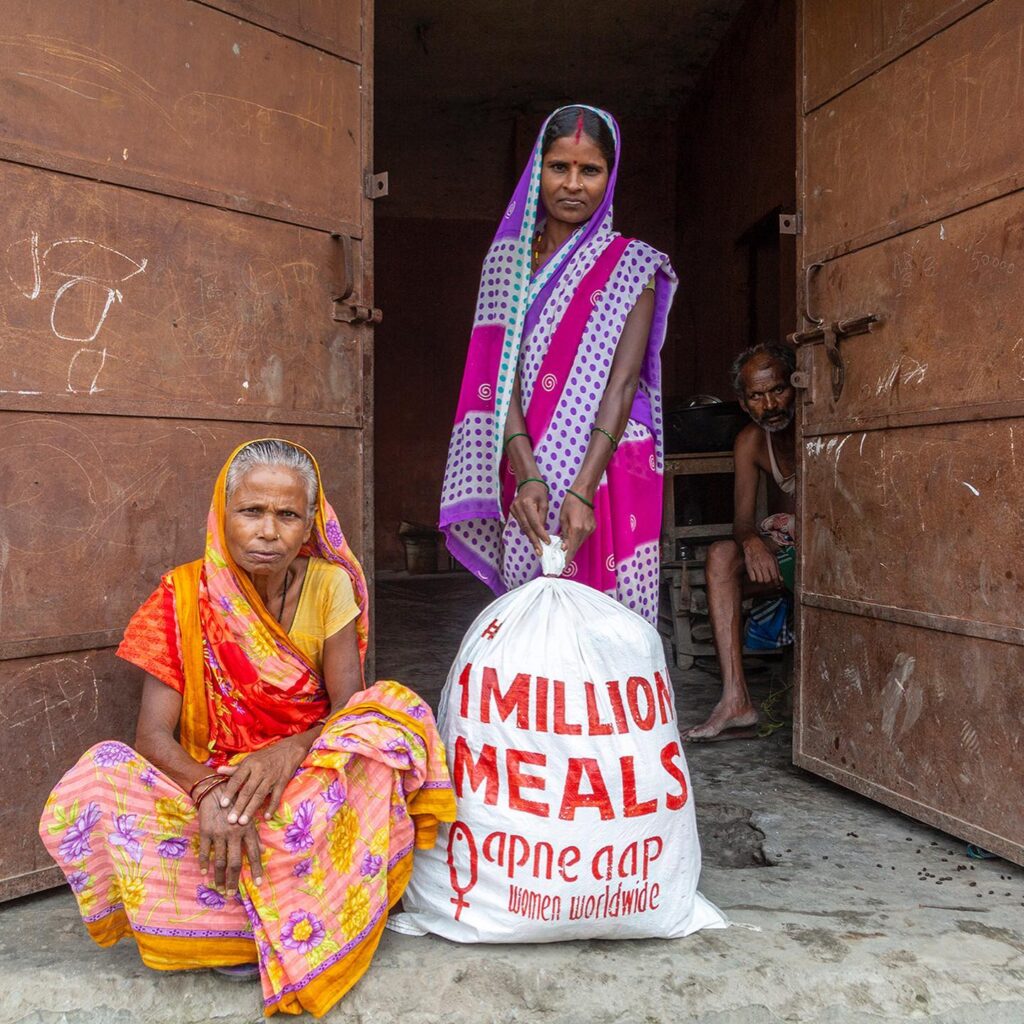 Two Indian women receiving food and supplies from Apne Aap NGO in India, an anti-sex trafficking organization supporting marginalized women.