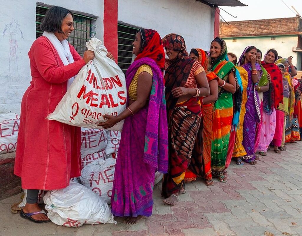 Ruchira Gupta, founder of Apne Aap NGO, distributing food to a group of Indian women in India, as part of efforts to combat sex trafficking and support marginalized communities.