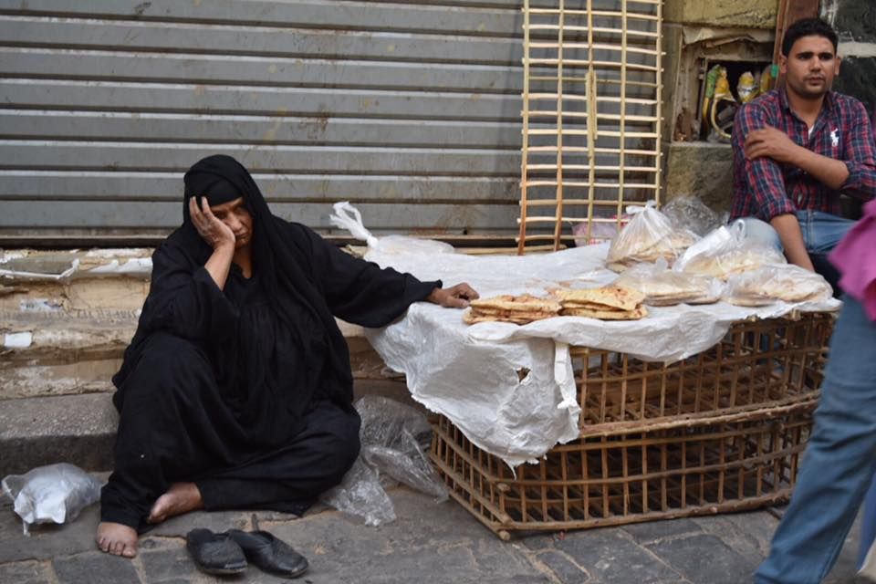 Egyptian woman sitting on the ground in a burka selling bread